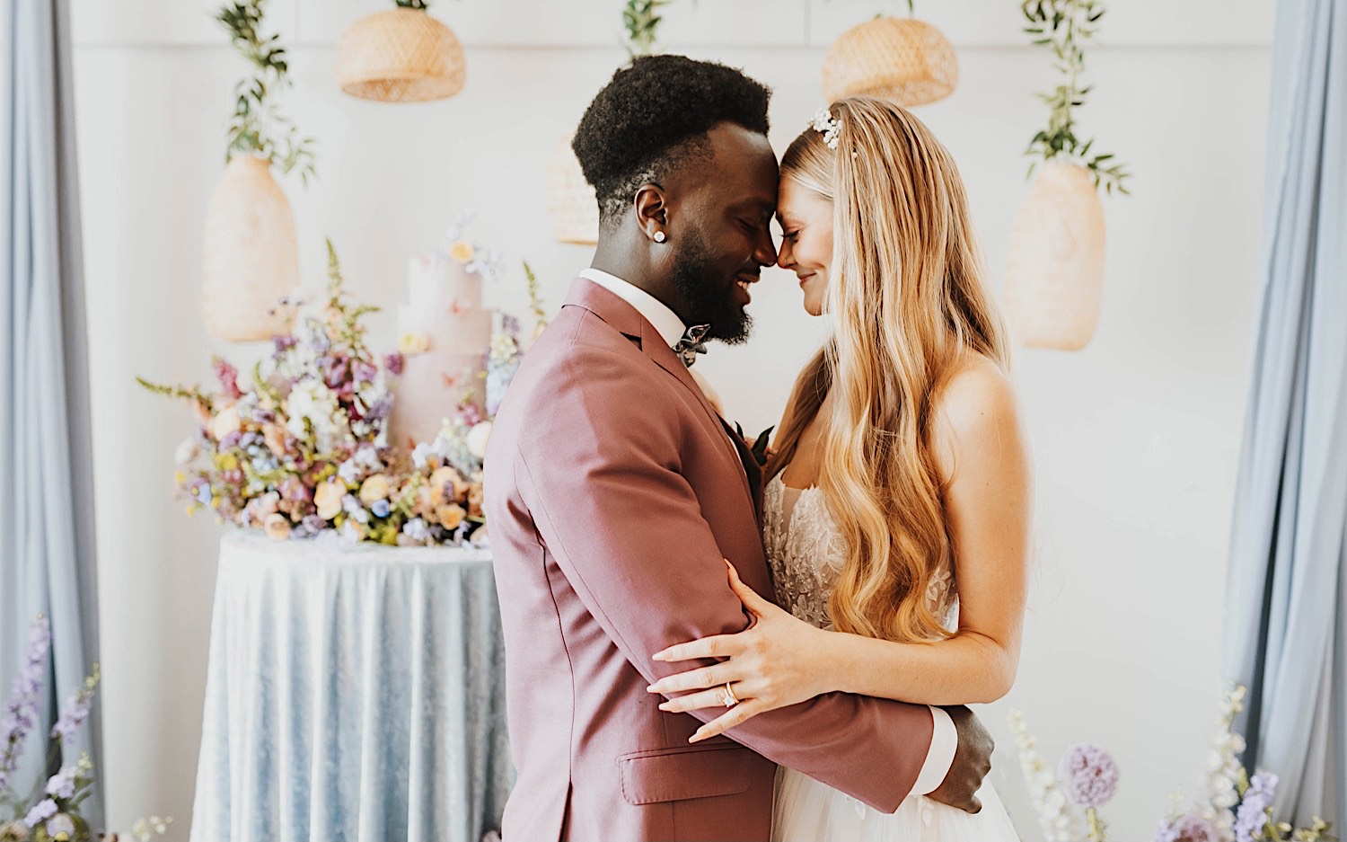 A bride and groom smile as they touch foreheads together while standing in front of their wedding cake during their reception at The Aisling A bride and groom smile as they touch foreheads together while standing in front of their wedding cake during their reception at The Aisling