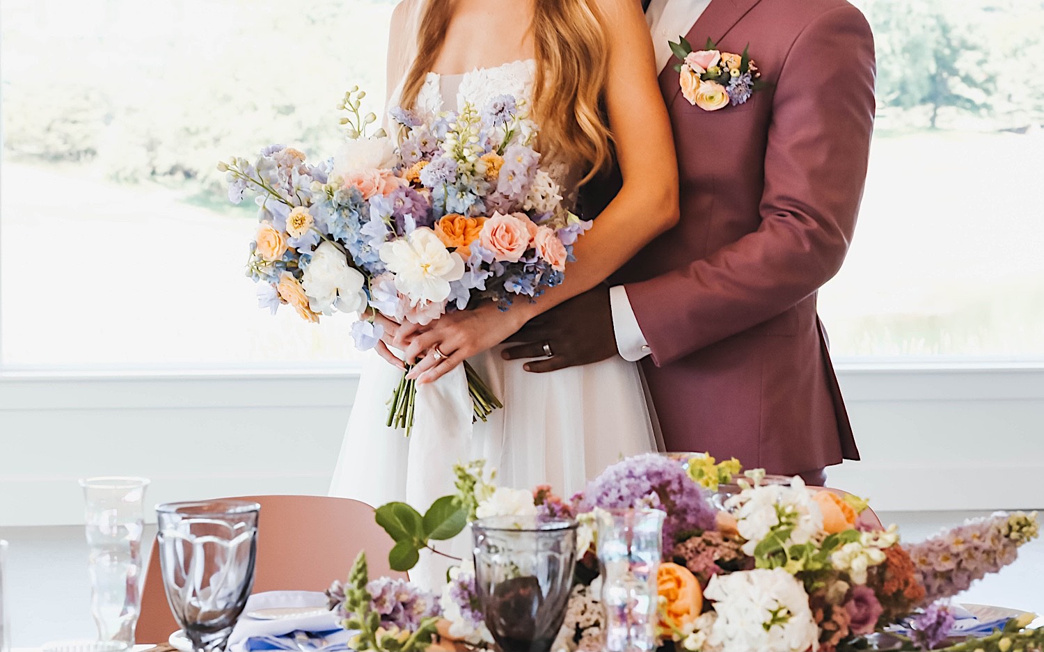 Torso photo of a bride and groom standing side by side next to their table during their wedding reception at The Aisling