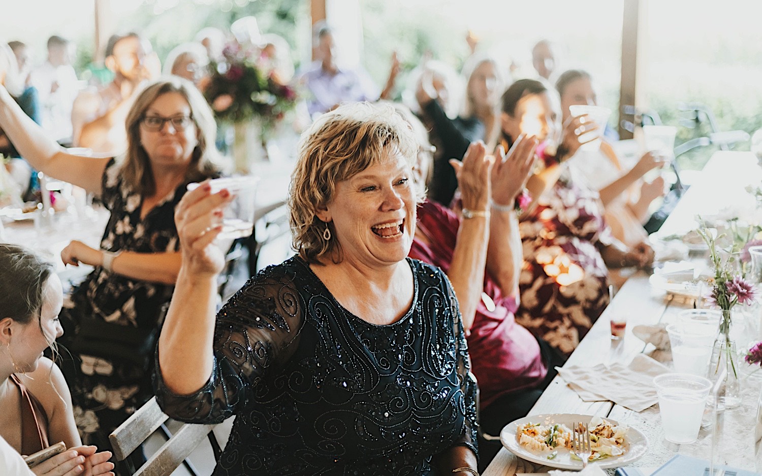 A woman cheers and raises a glass during a wedding reception at Legacy Hill Farm