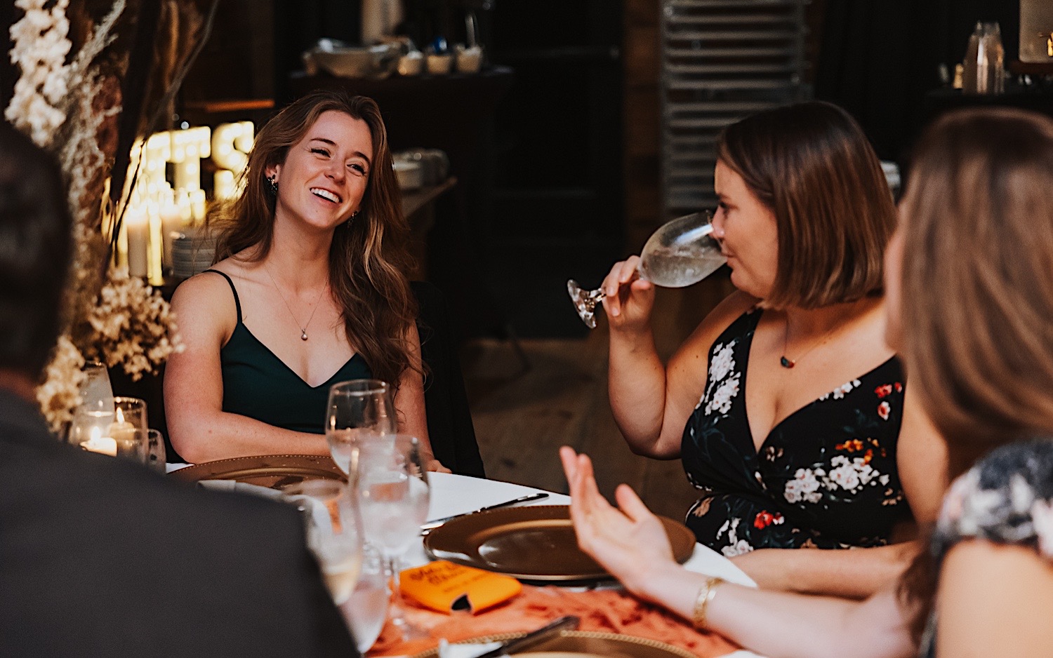 Guests of an indoor wedding reception at Lake Bomoseen Lodge in Vermont sit at their table and converse with one another