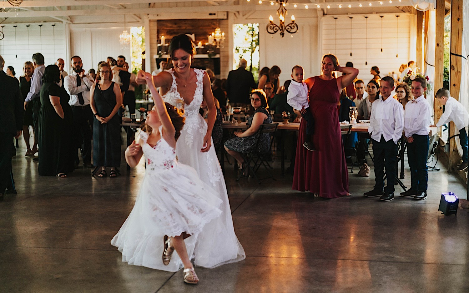A bride dances with a young girl during an indoor wedding reception at Legacy Hill Farm