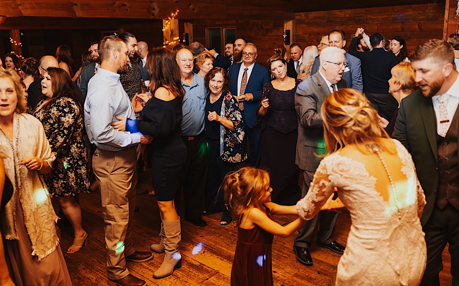 Guests of an indoor wedding reception at Lake Bomoseen Lodge in Vermont all dance and mingle together