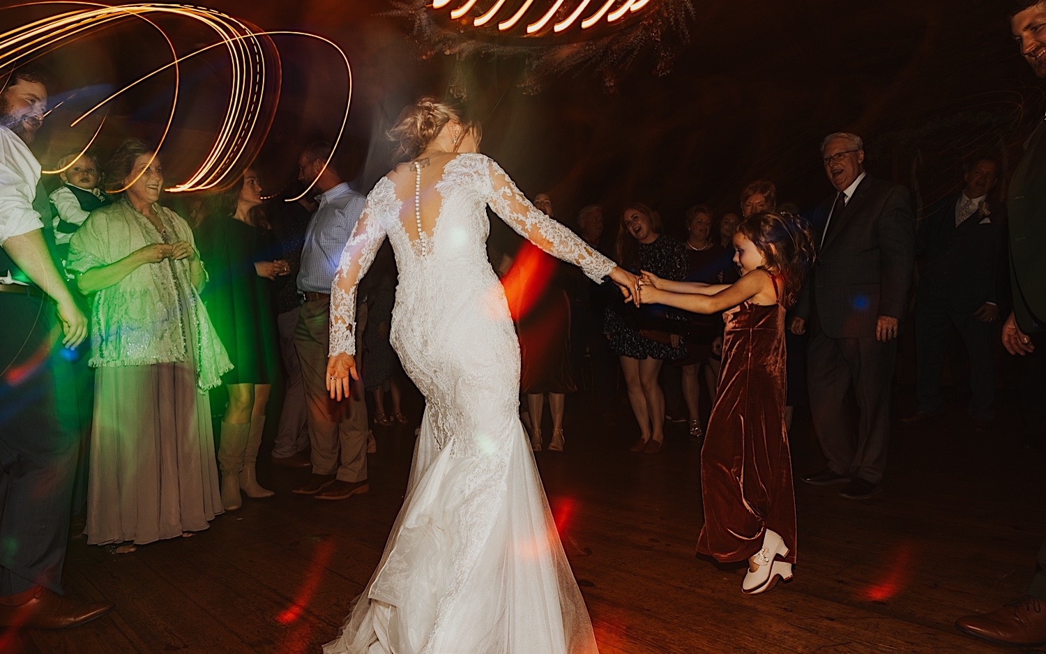 A bride dances with a young girl while in a dance circle during an indoor wedding reception at Lake Bomoseen Lodge in Vermont
