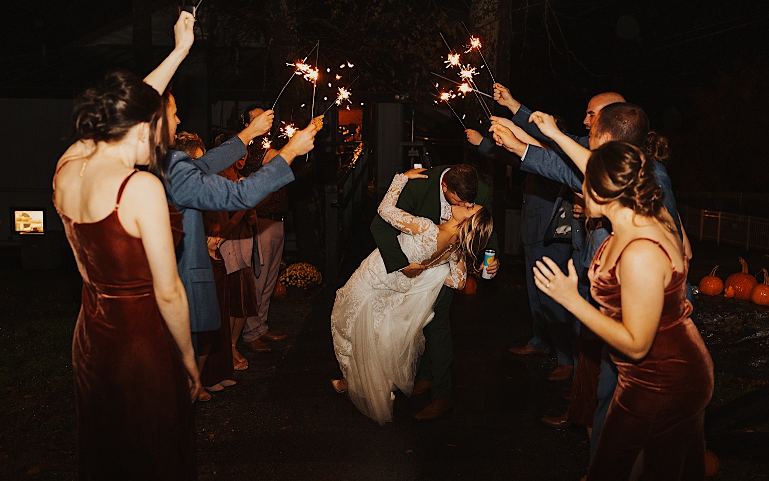 A bride and groom kiss while members of their wedding parties line their exit with sparklers as the two leave their wedding reception at Lake Bomoseen Lodge in Vermont